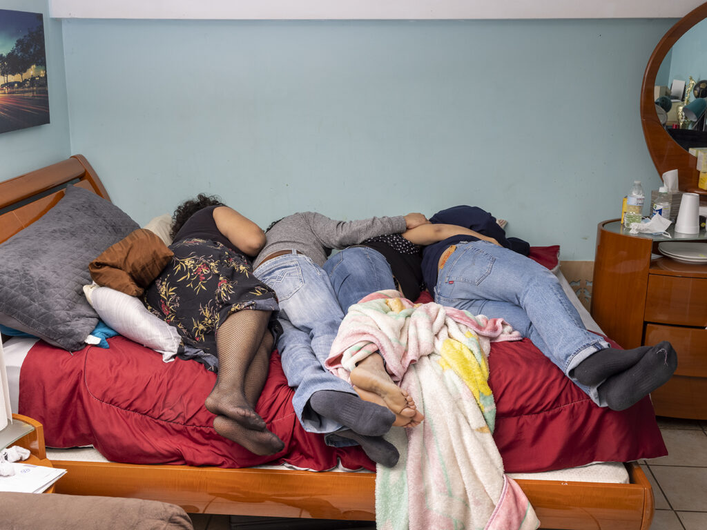 four people laying together in bed