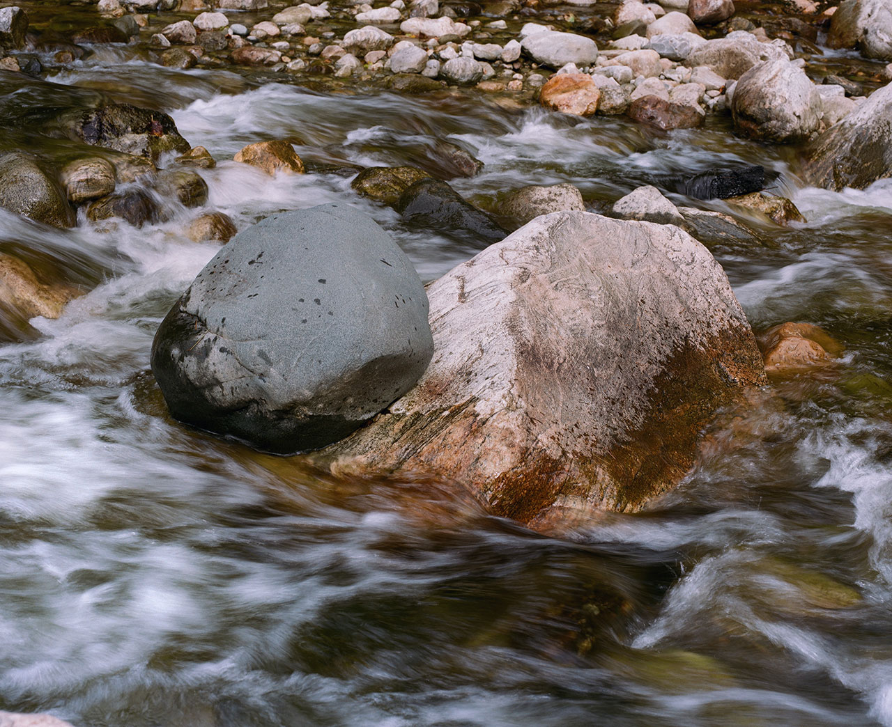 water flowing around stones in stream