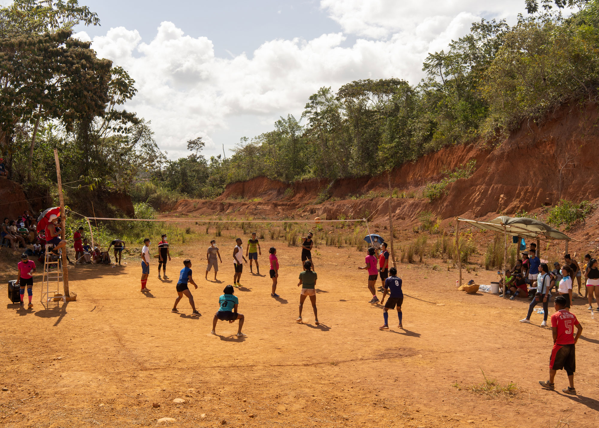 people playing volleyball on improvised dirt court