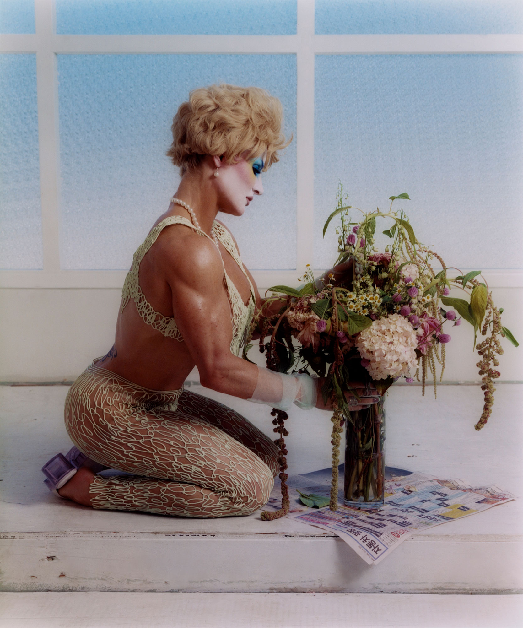 person sitting on knees holding flowers in a vase