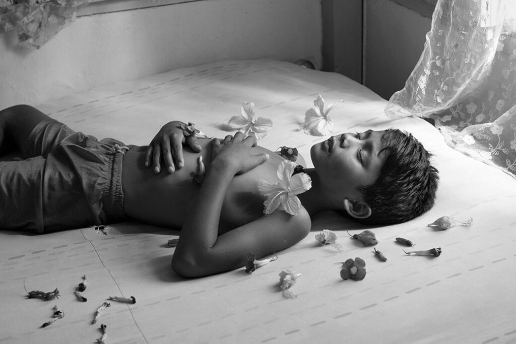 child laying on bed covered and surrounded by flowers