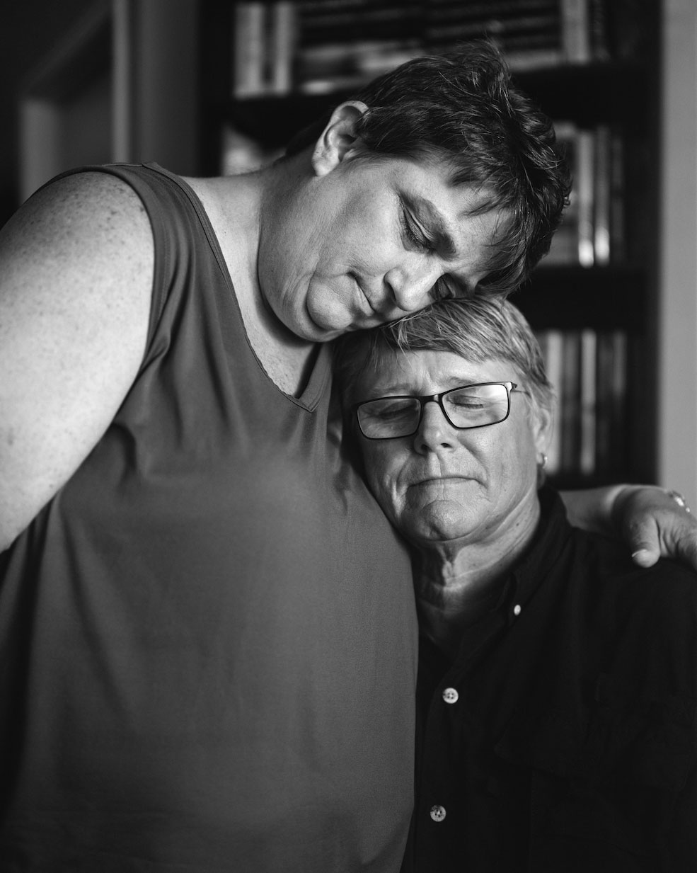 two adults in an embrace, one with arms around the other