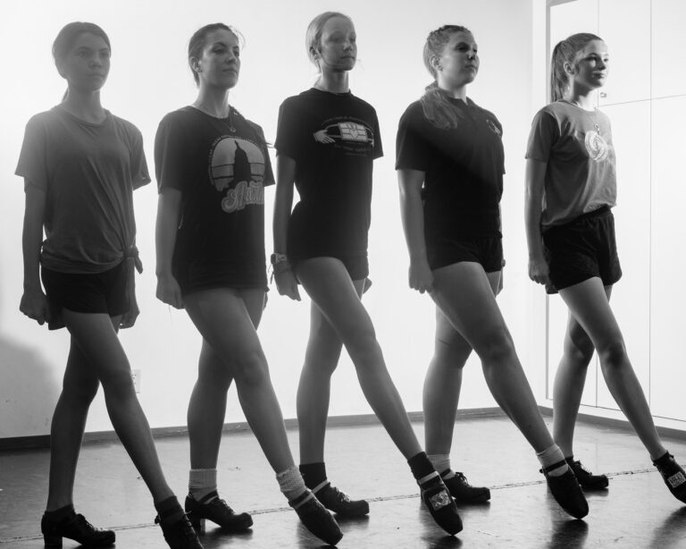 black and white image of five teenagers standing in line with their right feet forward and pointed in dance-ready position