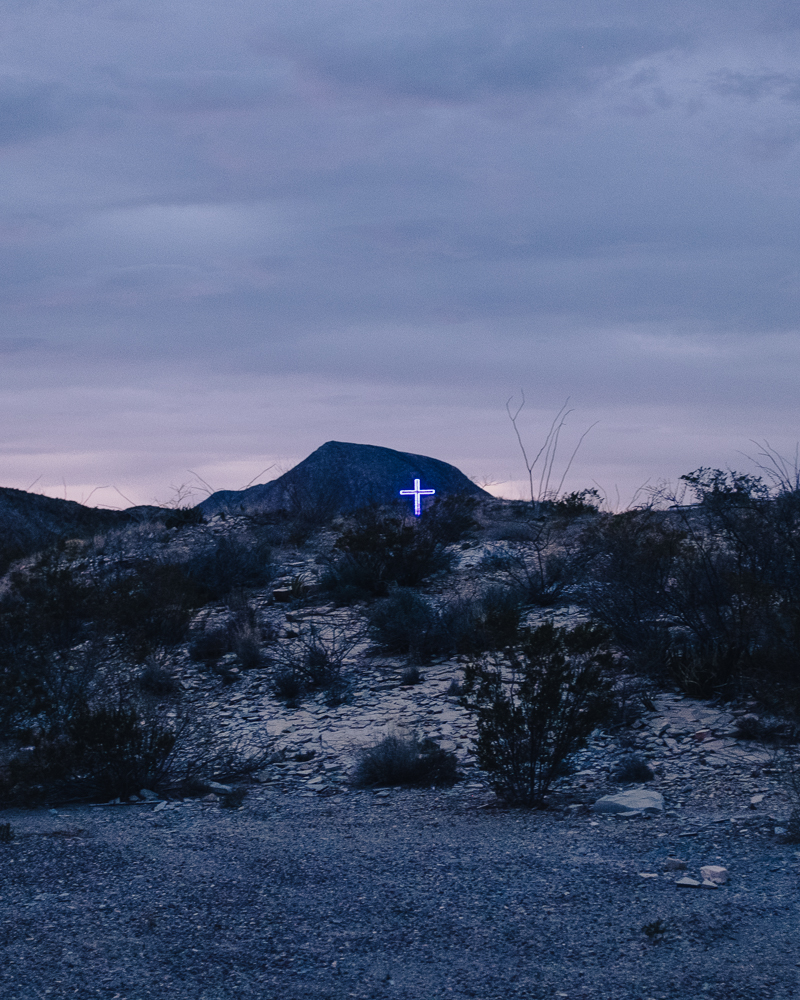 cross lit by fluorescent light around perimeter in desert landscape at dusk