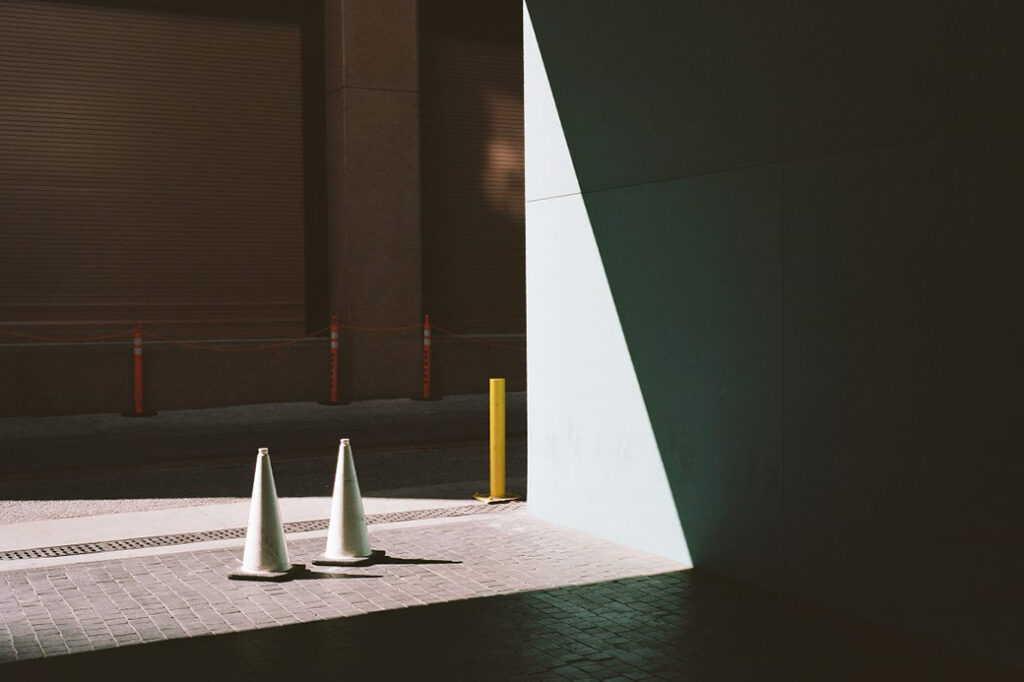 two white traffic cones on side of building entrance illuminated by light