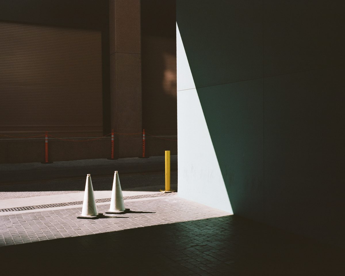 two white traffic cones on side of building entrance illuminated by light