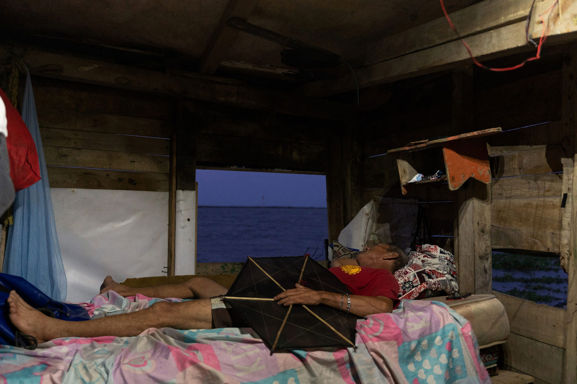 person laying in bed in small room holding six-sided geometric object