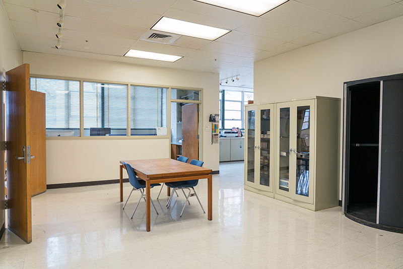 area of Photography Lab that includes table and chairs, equipment cabinet, and entrance to darkroom