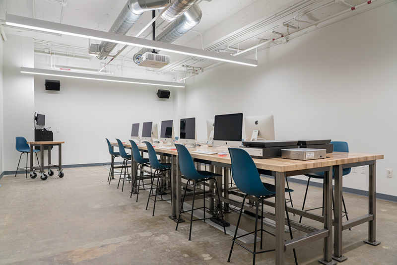 digital media lab that features a large island work space with multiple computer stations