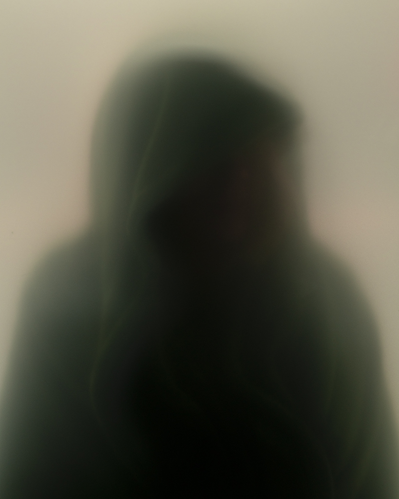 blurred faceless human figure wearing dark hoody