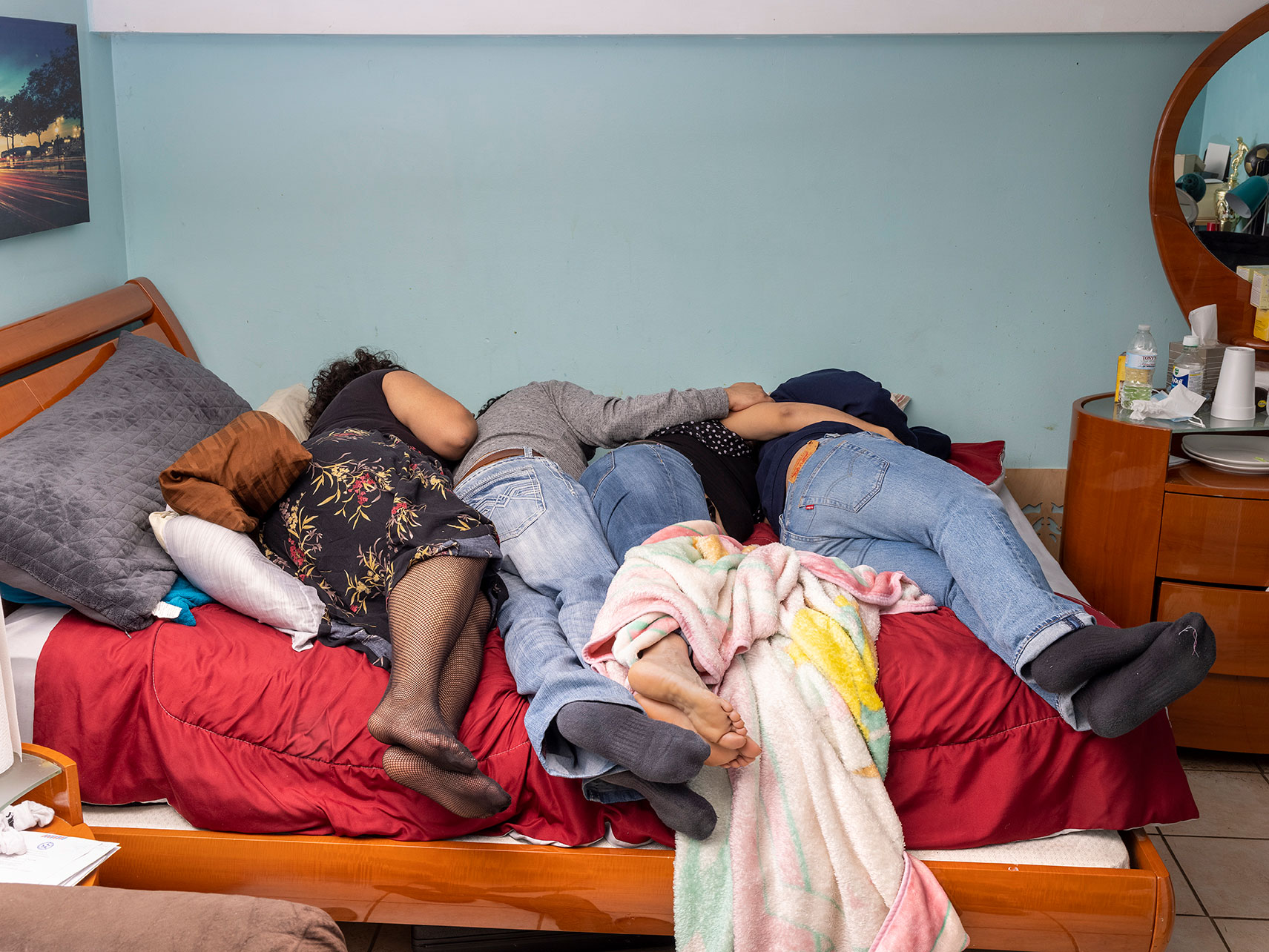 four people laying together on a bed