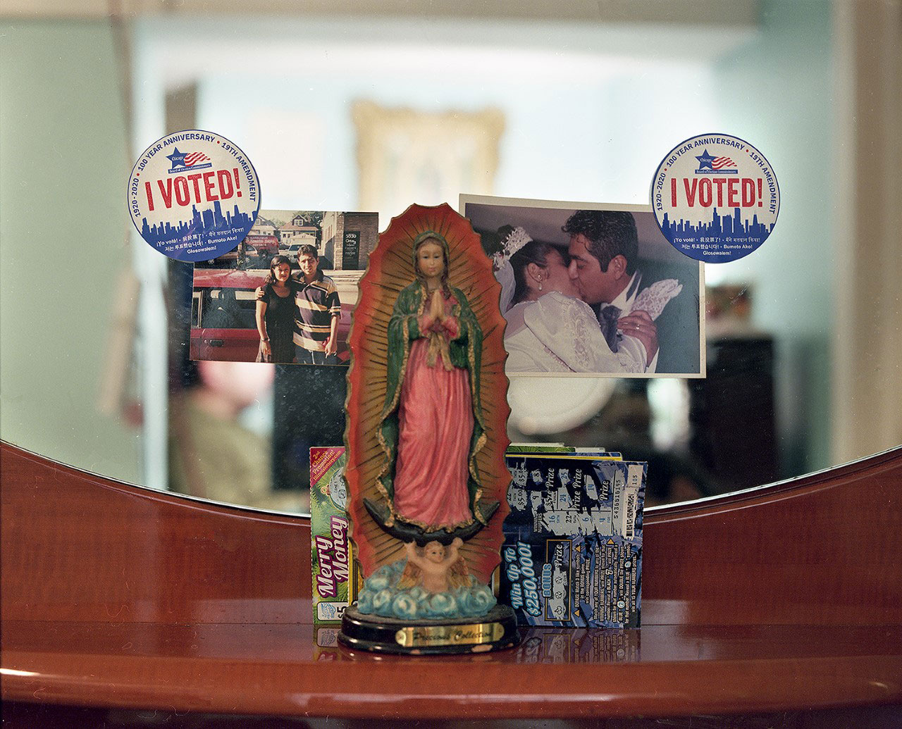 virgin statue on dresser in front of family photos and two stickers that read I voted!