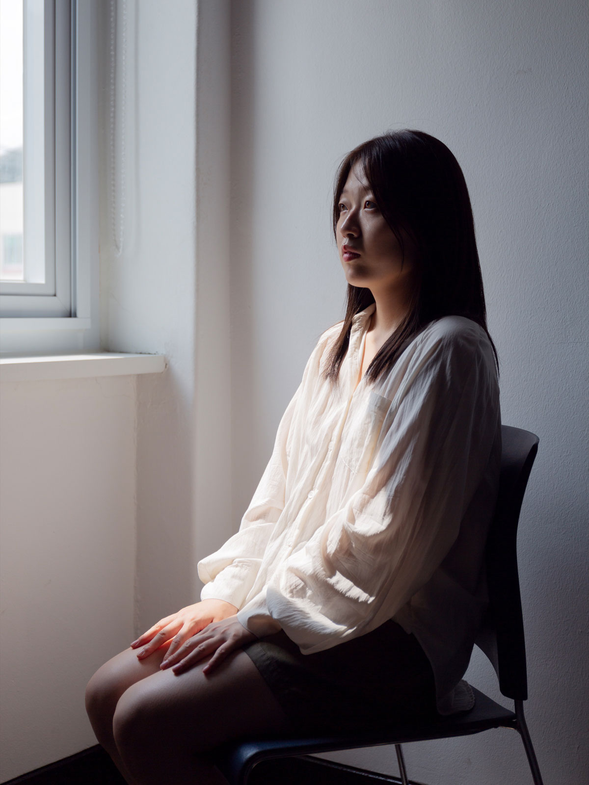 person sitting in chair being illuminated by light from nearby window