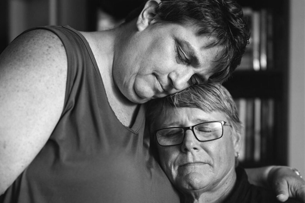 two adults in an embrace, one with arms around the other