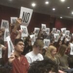 Low quality cell phone photograph of hundreds of UT student holding up "NO" signs at the Sexual Misconduct Town Hall Spring 2020.
