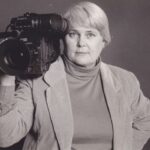 Trella Ann Laughlin holding a video camera on her shoulder.