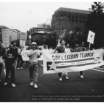 Dennis Medina marching with Gay and Lesbian Tejanos at the 1987 March on Washington for Lesbian and Gay Rights. A few people hold signs and the two people in front hold a large banner.
