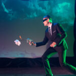 three actors on dark stage in futuristic costumes