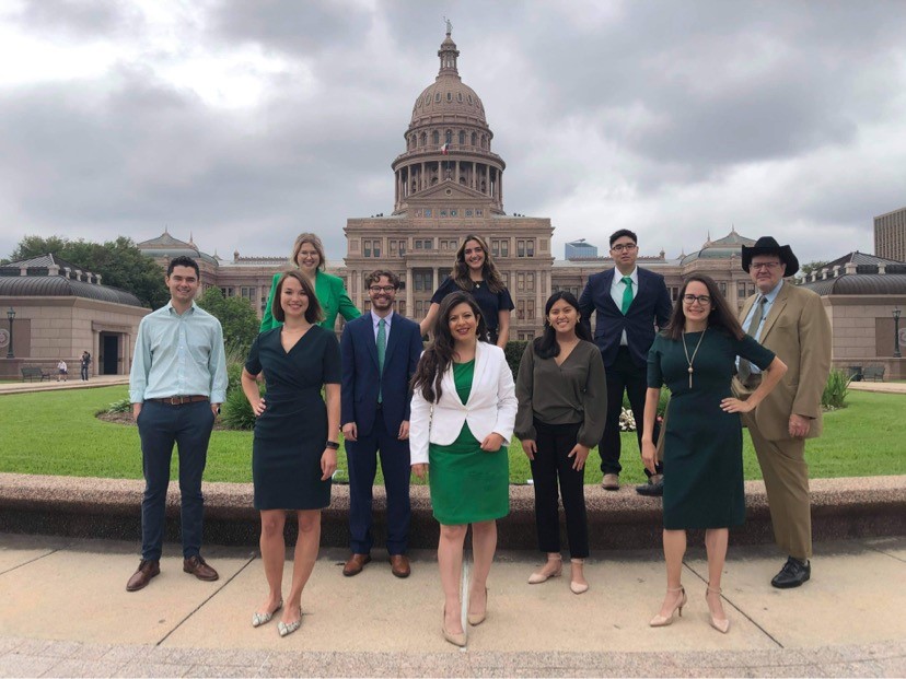 A group of people posing in front of a large building