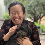 Quỳnh-Hương Nguyễn smiling and holding a small brown dog.