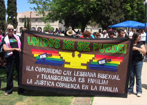 Queer protesters display a sign in a park