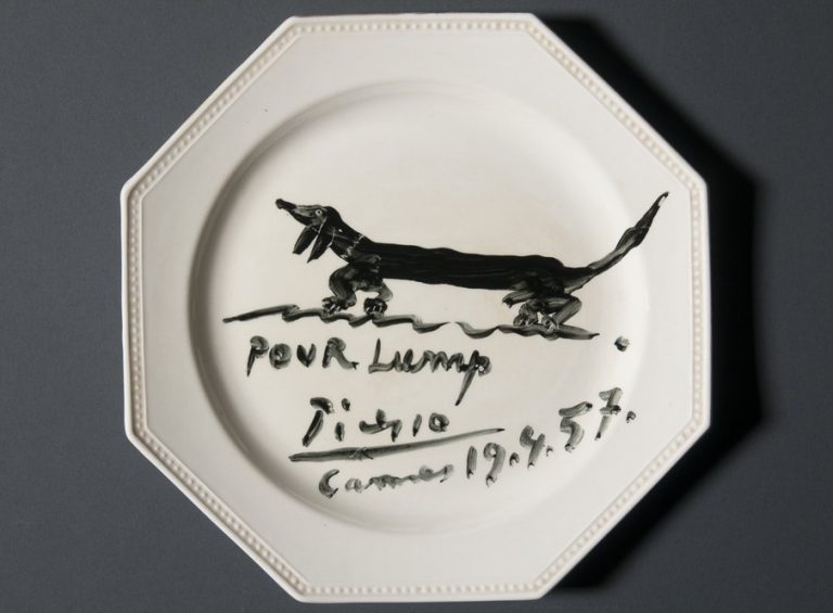 Souvenir luncheon plate painted by Pablo Picasso and dedicated to Lump, David Douglas Duncan's dachshund. Black glaze on commercial ceramic plate. 24 cm. in diameter. April 19th, 1957. Photo by Pete Smith. Image courtesy of Harry Ransom Center.