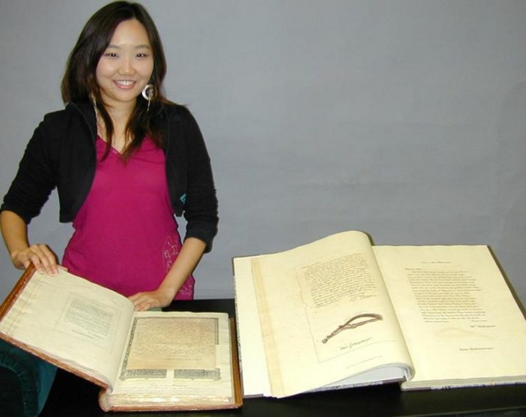 Inkyung Youm, a graduate intern in the Ransom Center's Conservation Department, with the printed and facsimile versions of William Henry Ireland's handiwork, "Miscellaneous Papers and Legal Instruments under the Hand and Seal of William Shakespeare" and "Fabricated Shakespearian Manuscripts."