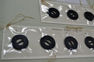 Strips of Mylar containing weights removed from the burgundy ball gown. Each compartment is documented with the weight’s original location on the dress.