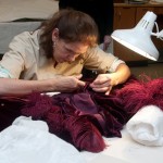 Cara Varnell, independent art conservator, repairs the burgundy ball gown. Photo by Pete Smith.