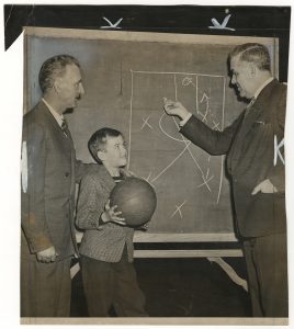 Clair Bree (left) and Howard Cann diagram play for a basketball clinic. "New York Journal-American," December 12, 1948.