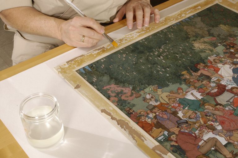 Softening adhesive on the border of the drawing, "The Christening Party" by W. H. Robinson. Photo by Eric Beggs.