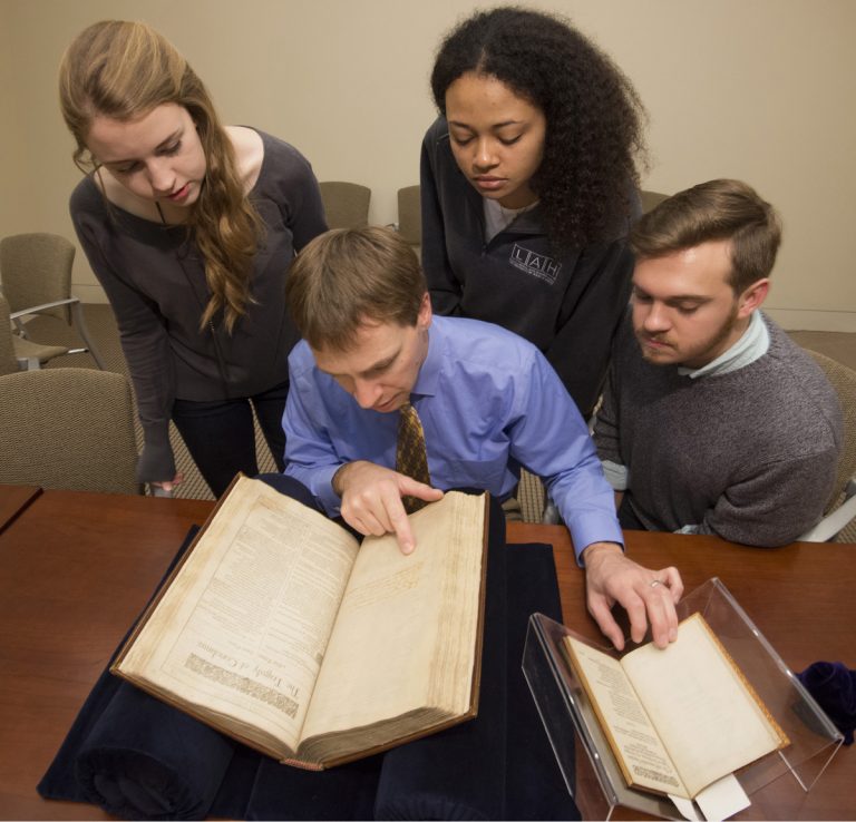 Elon Lang, seated in the center, and undergraduates from "Drama in the Archives" view collection materials. Students, clockwise from upper left, are Lily Pipkin, Haley Williams, and Kenneth Williams. Photo by Pete Smith.