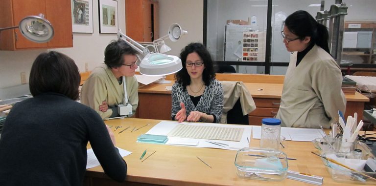 Conservators and volunteers discussing techniques for removing stiff paper repairs