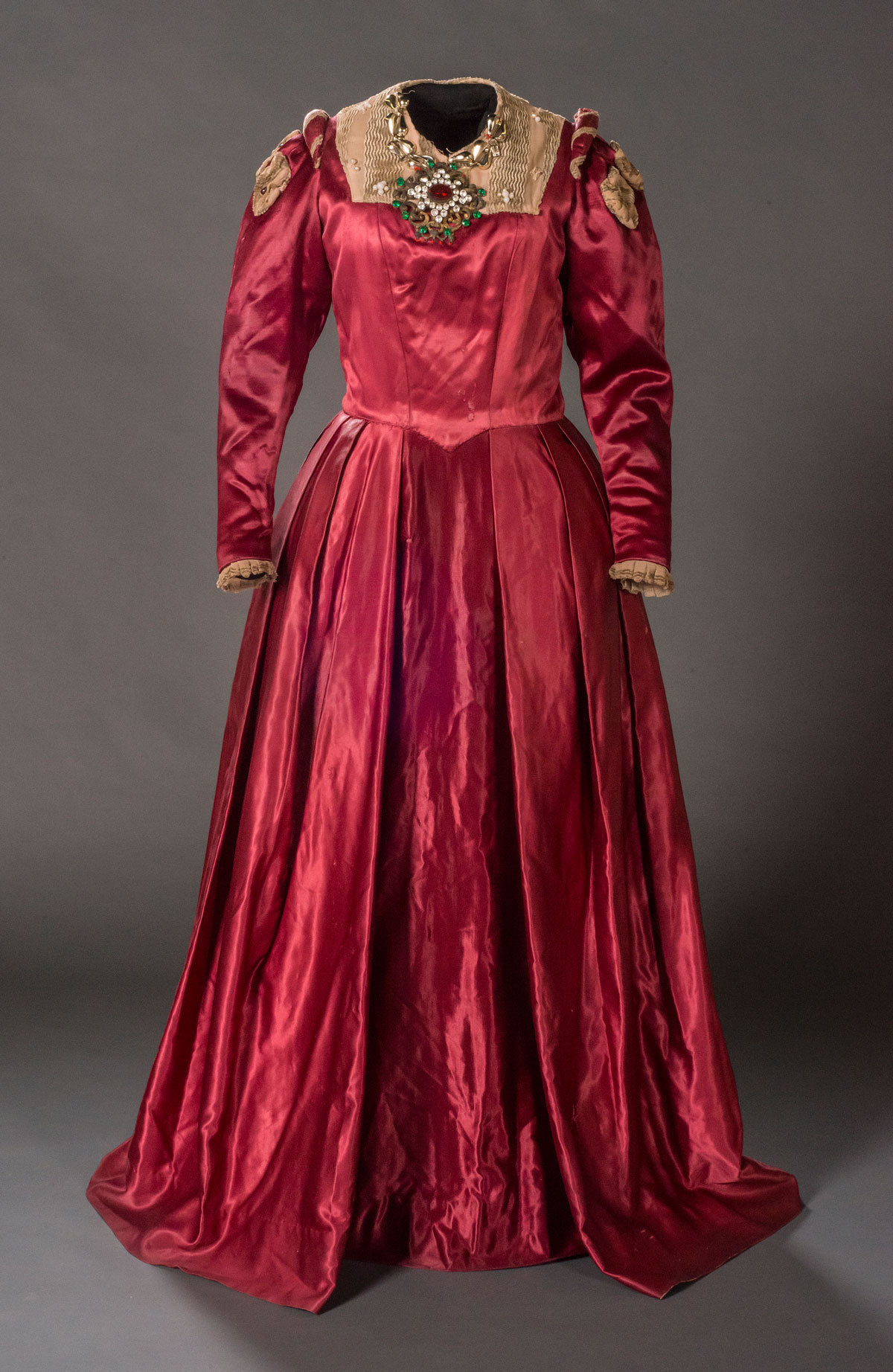 Unidentified maker. A gown worn by Rosalind Iden in the role of Beatrice in Much Ado about Nothing, ca. 1945 Textile, metal, and glass. Donald Wolfit Costume Collection, Harry Ransom Center Links from a gold-tone necklace owned by Rosalind Iden are sewn around the neckline of this gown. All of the costumes in the Wolfit archive bear marks of extensive wear, reuse, and repair, reflecting the constant use and hectic schedule of Wolfit's touring company. Because the company’s costumes were largely created or chosen for ease in traveling and interchangeability with various productions, they were not renowned for their opulence, innovation, or craft. Critic Caryl Brahms described a visit to the costume storage at Wolfit's offices as “a stock of dip-in-and-grab-one costumes ‘suitable for Shakespeare’ [that] are in a constant state of being repaired.”