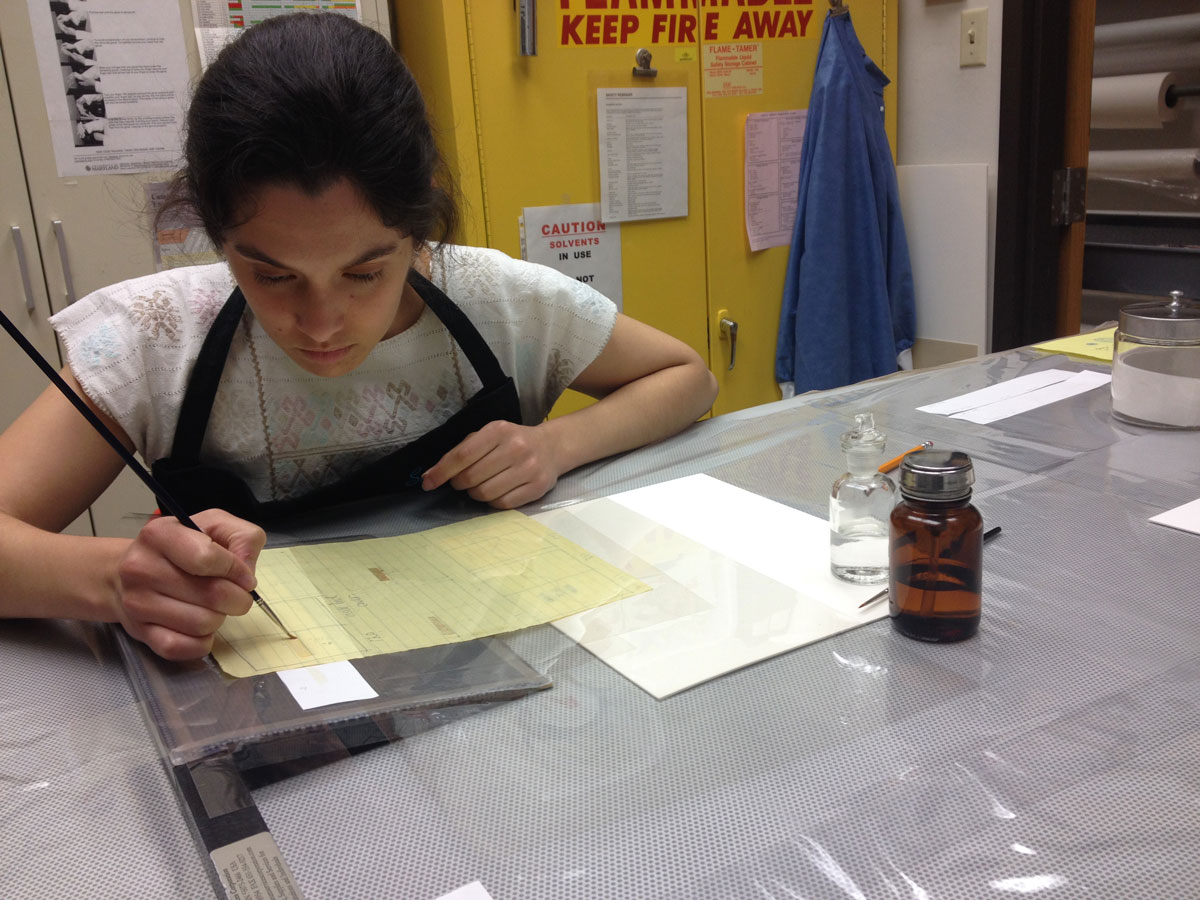 The author reducing the orange adhesive stains with solvents using the suction table.