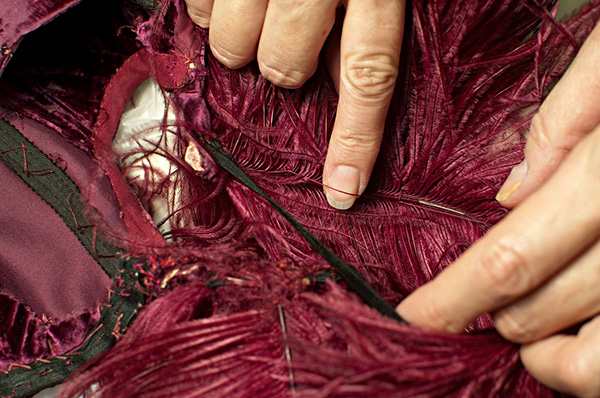 Ostrich feathers in burgundy ball gown from Gone With The Wind, here being repaired by Cara Varnell, independent art conservator (2011). Harry Ransom Center, University of Texas at Austin. Photo by Pete Smith.