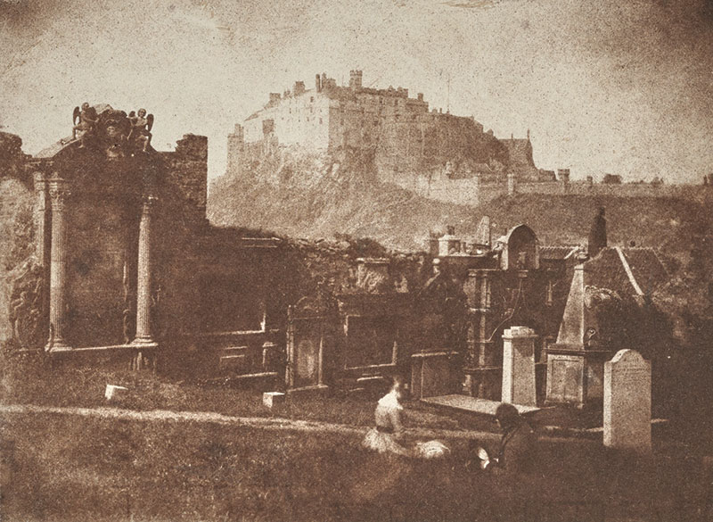 Churchyard with people seated on ground and castle in background