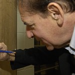 Alan Furst signs the authors' door during a visit to the Ransom Center. His name joins other notable authors who have visited and signed the door, including Tennessee Williams, Arthur Miller, Larry McMurty, Gore Vidal, and Norman Mailer.