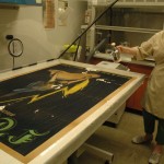 Bedford sprays a water-alkaline solution on the poster as part of washing process to remove acidity.