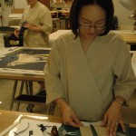 Volunteer Nani Lew cuts and prepares strips of Japanese paper for attachment to the poster.