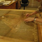 Head of Paper Conservation Stephanie Watkins aligns the poster before attaching the backing paper.