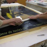 Once the poster has been aligned, Watkins and Bedford remove the Mylar cover.