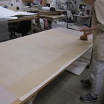 Watkins applies adhesive to the Japanese paper before adhering it to the poster.