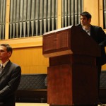 At the podium, Jake Silverstein reads an excerpt from Wallace's essay "A Supposedly Fun Thing I'll Never Do Again." Kurt Hildebrand reads the footnotes for the piece.