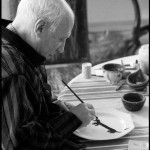 Upon learning that Lump, David Douglas Duncan's dachshund, had never had a plate of his own, Pablo Picasso took the luncheon plate in front of him and began painting the dog's portrait on it. La Californie, Cannes. Gelatin silver negative. April 19th, 1957. © David Douglas Duncan.