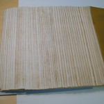 Repairing the spine folds of the gatherings. The spine folds of the gatherings are reinforced by adhering long fiber paper strips around each fold with paste. This process strengthens the gatherings so they can be sewn without tearing.