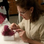 Varnell mends an original feather that broke at the point where it was stitched to the gown. Photo by Pete Smith.