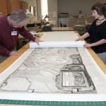 Associate Director for Conservation and Building Management Jim Stroud and Hamilton carefully roll a protective layer of paper on top of the map. Photo by Pete Smith.