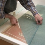 Jim Stroud pulls back the lining fabric while holding the poster securely with a tool. Photo by Pete Smith.