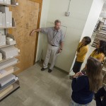 Watson points out the Ransom Center's authors’ door, which is frequently signed by visiting authors and artists, during an orientation session for new graduate interns. Photo by Pete Smith.
